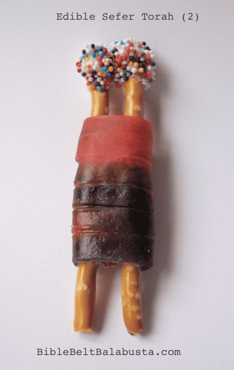 A photo of a mini Torah scroll made out of wrapping pretzel rods in a fruit roll-up.