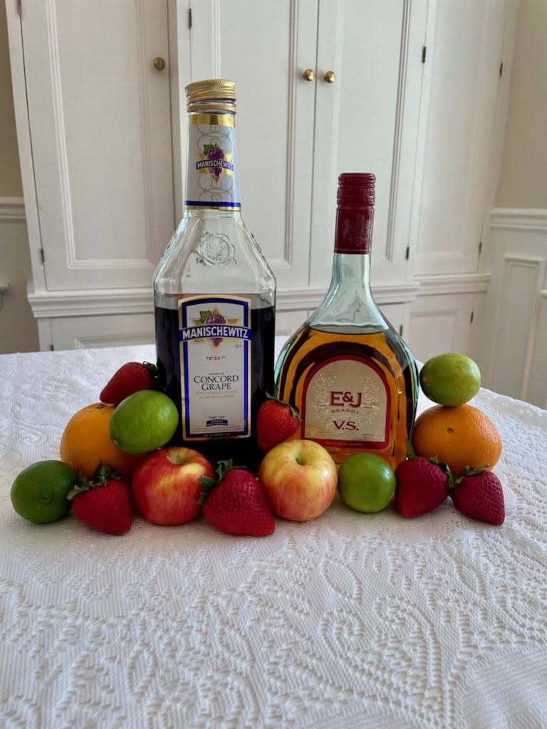 A photo of a bottle of wine, another bottle of alcohol, and apples.